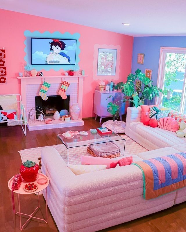 A dopamine decor living room with a bold pink and periwinkle accent wall, a fireplace, a sitting area, colorful pillows and blankets, and eye-catching decor
