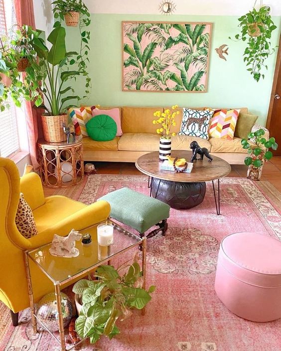 A dopamine decor living room with a bright green accent wall, a yellow sofa, a bold yellow chair, a pink rug and ottoman, and a green ottoman