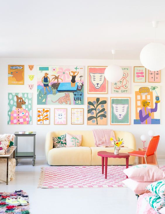 A dopamine decor living room with a bright yellow sofa, orange chair, colorful gallery wall, statement rug and pillows