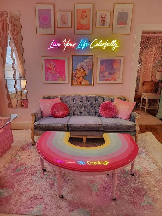 a dopamine living room with blush walls, a gray sofa with pink pillows, neon lights and a bright gallery wall