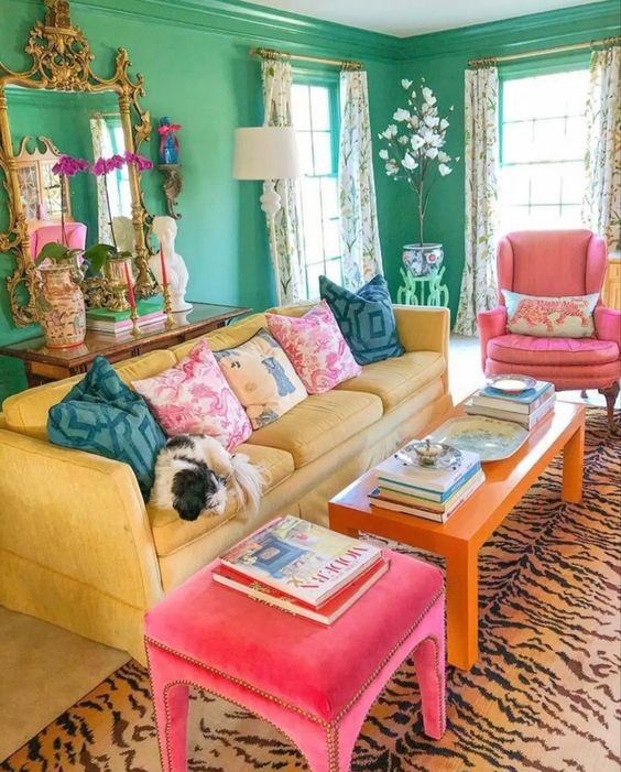 a dopamine living room with green walls, a yellow sofa, an orange table and pink chairs, a printed rug and sophisticated decor