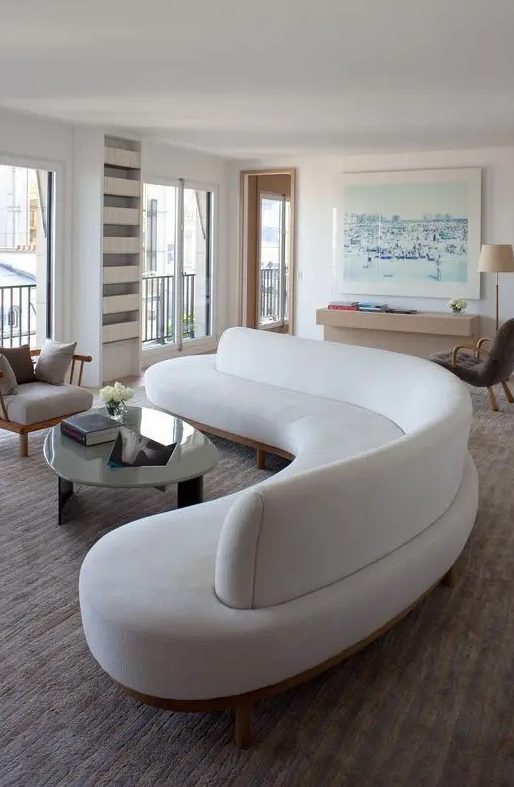 A beautiful, curved white sofa takes up the entire living room, giving it soft lines and shapes