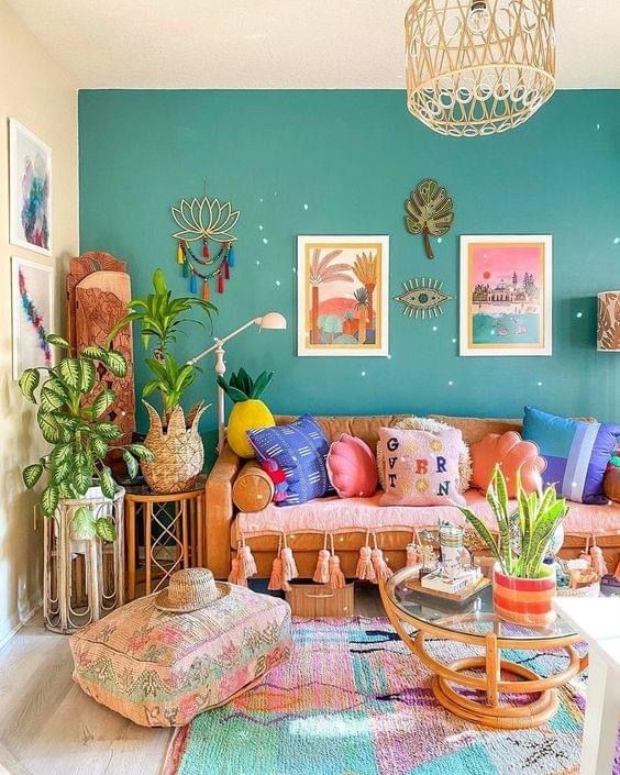 A beautiful living room in dopamine decor with a green accent wall, a pink sofa with colorful pillows, rattan tables, a statement rug and pastel-toned artwork