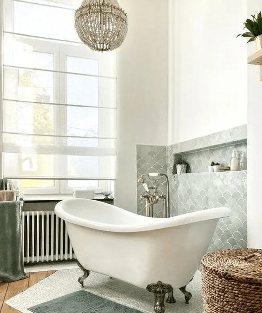 a beautiful bathroom with a light green fish scale backsplash, a freestanding bathtub, a basket and some rugs