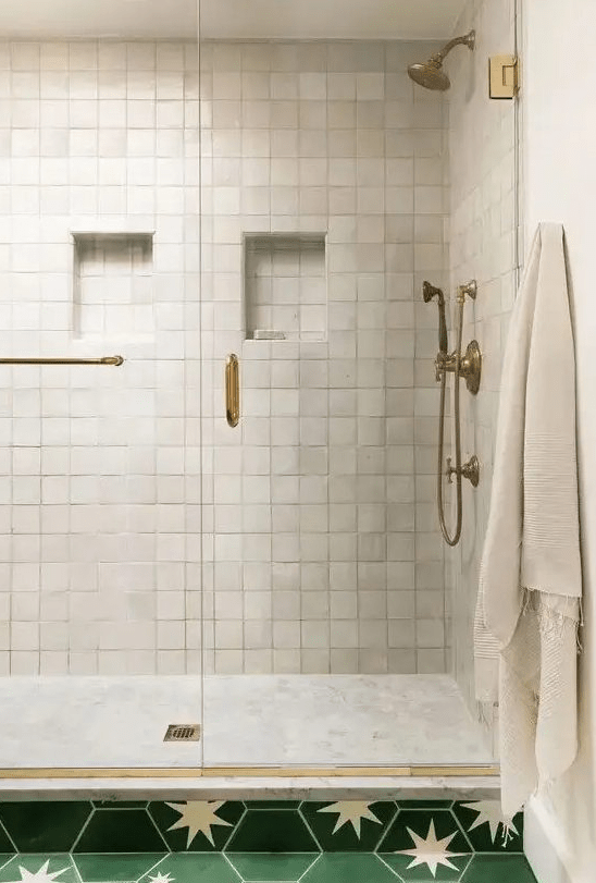 A beautiful shower area clad in neutral zellige and marble tiles with chic brass touches to add a touch of vintage to the room