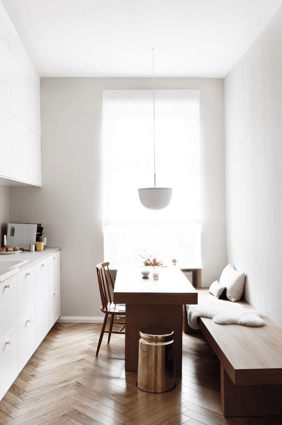 a minimalist space with a comfortable bench and a dining table that can also be used as a kitchen island