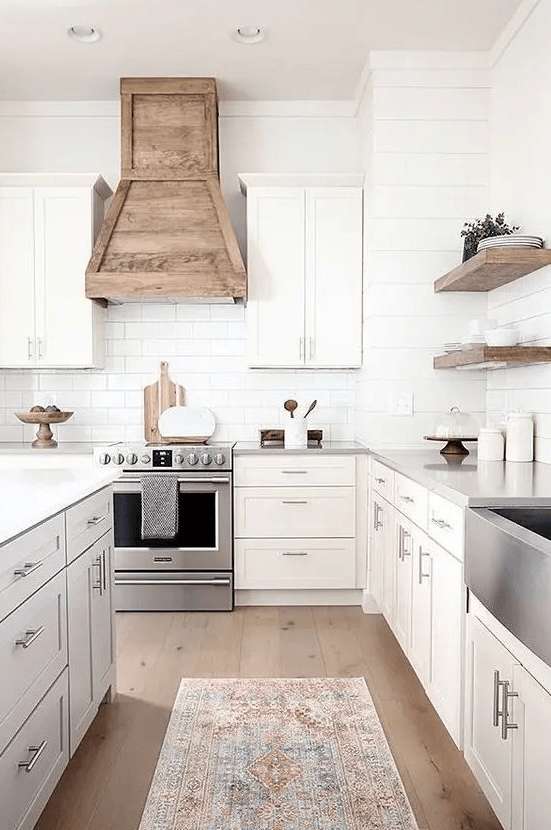 a modern farmhouse kitchen with shaker-style cabinets, a white subway tile backsplash, a wood hood, and floating shelves