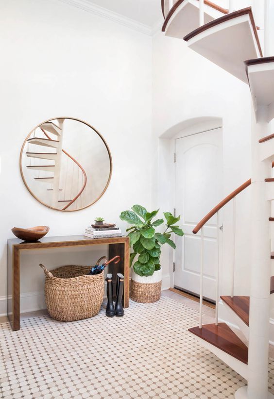 a modern entryway with an elegant wooden console, a round mirror, some baskets and an eye-catching plant