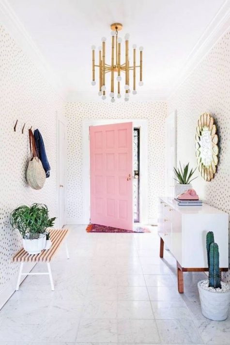 a modern, playful and whimsical entryway with polka dot walls, a white sideboard, bench, clothes racks and a mirror
