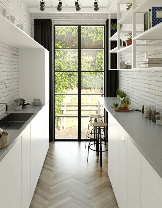 a modern white gallery kitchen with elegant cabinets, gray stone countertops, open shelving and brick walls