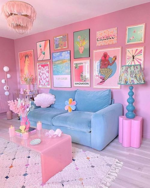a pink dopamine living room with a pastel blue sofa, a statement gallery wall, a pink coffee table, a pink chandelier and a blue lamp