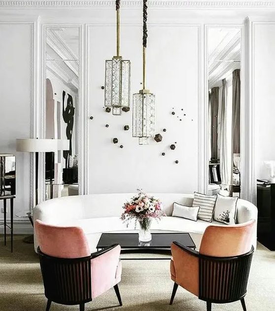 a sophisticated white sofa with a curved silhouette, peach colored curved chairs, unique pendant lamps and wall decoration for an elegant space