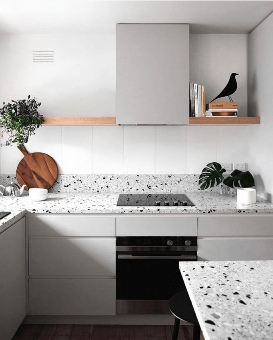 a calm Nordic kitchen with light gray cabinets and matching gray terrazzo countertops and a long open shelf in place of the top