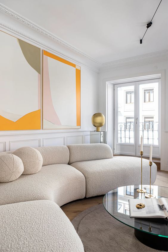 a tranquil living room with a cream bouclé sofa, a round coffee table, large abstract art and some brass decor