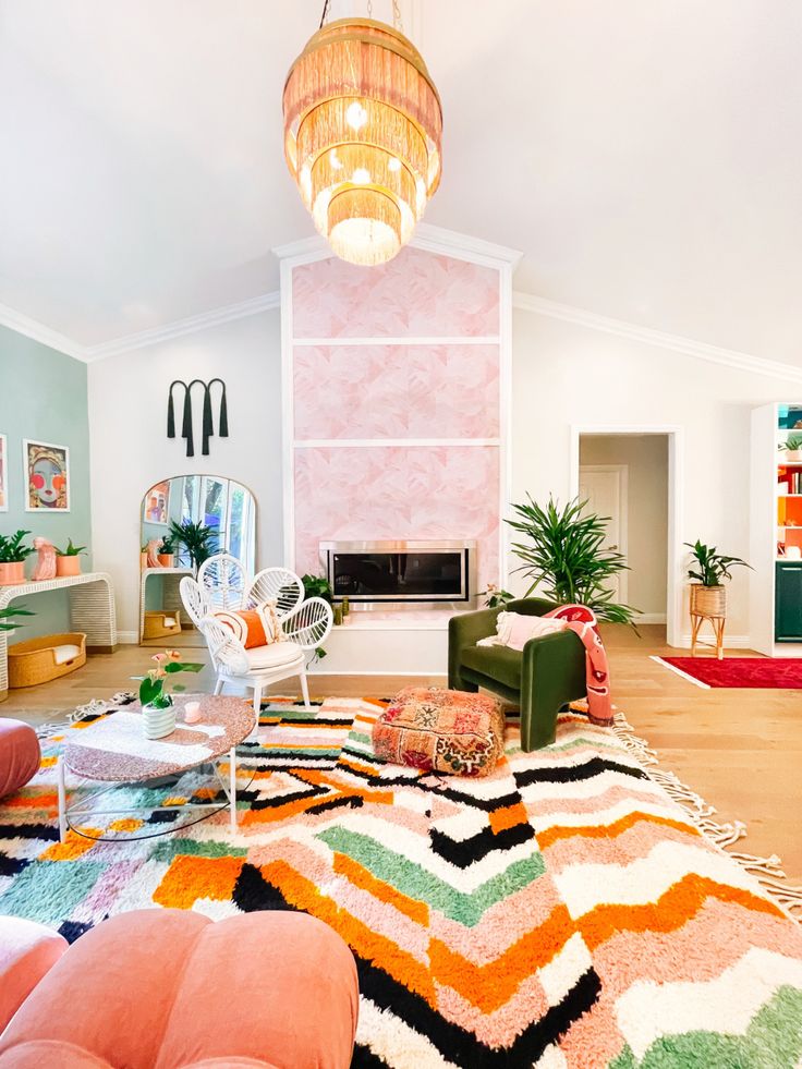 a vibrant living room with a statement rug, a fireplace with pink potted plants, a dark green chair and a peach sofa