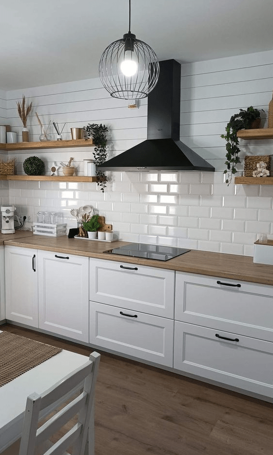 a white Nordic kitchen with shaker cabinets, a white subway tile backsplash, open shelving and a black range hood