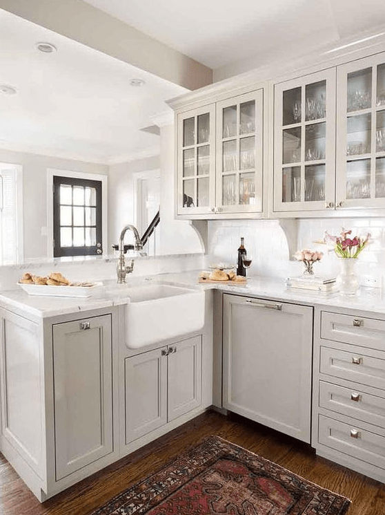 an airy gray kitchen with marquetry and glass cabinets, a white subway tile backsplash, and white quartz countertops