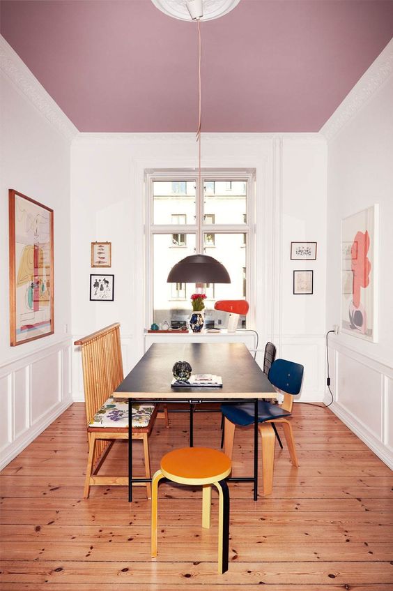 an exquisite dining room with a purple ceiling, a black table and mismatched chairs, some cool artwork