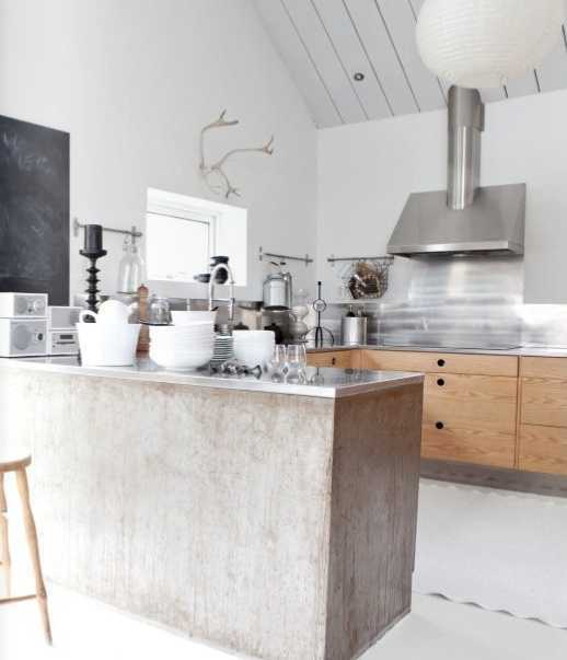a Scandinavian kitchen with stained cabinets, a shabby-chic island, stainless steel appliances and black accents