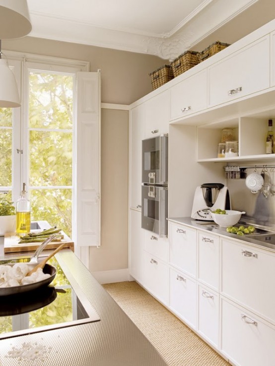 a modern white kitchen with sleek cabinets, a kitchen island, metal countertops and backsplash, and some baskets for storage