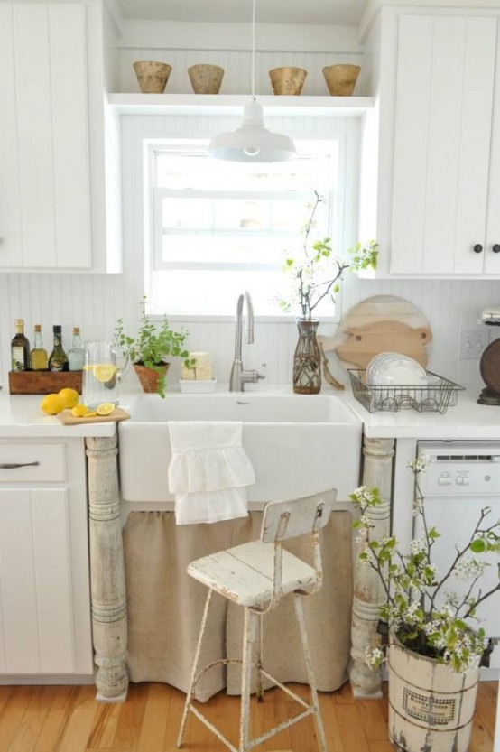 a white country kitchen with boarded cabinets, a vintage sink with a stand, pots and green plants