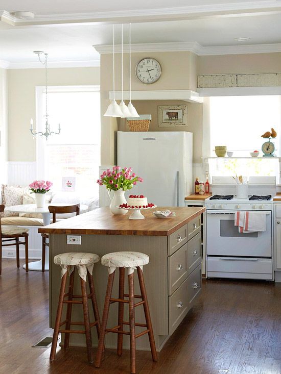 a neutral farmhouse kitchen with butcher block countertops, pendant lamps, stools, and white appliances