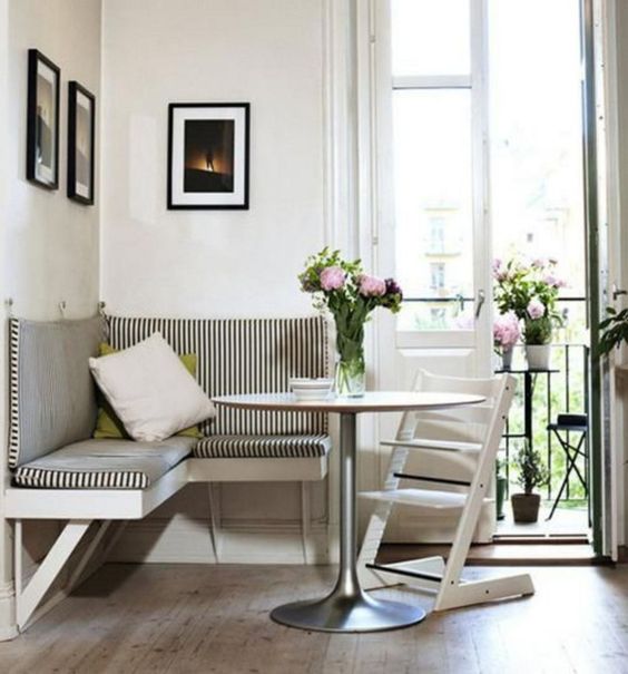 a small corner nook with a striped wall seating area and a small table, a folding chair and a gallery wall as well as some flowers