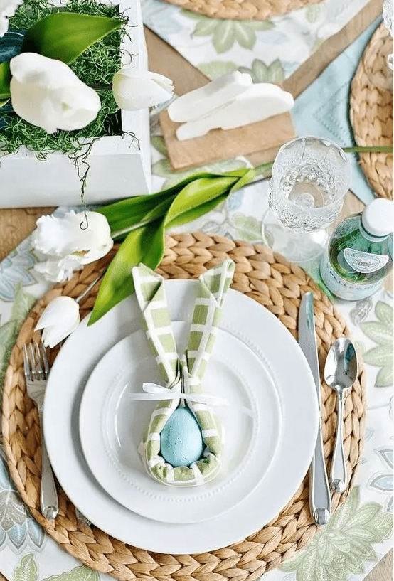a chic Easter table setting with botanical placemats, woven placemats, pastel napkins, white tulips and eggs