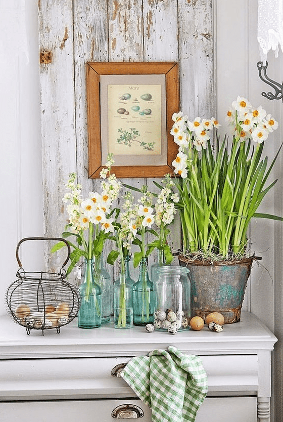 A console of fresh flowers in clear vases and a bucket and a nest of real eggs are great for spring and Easter