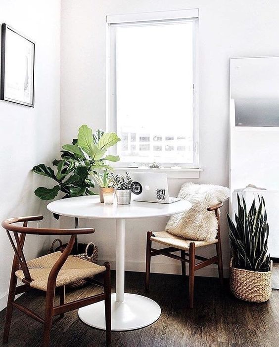 A beautiful modern breakfast nook with a few comfortable chairs, a round table and some plants invites you to linger