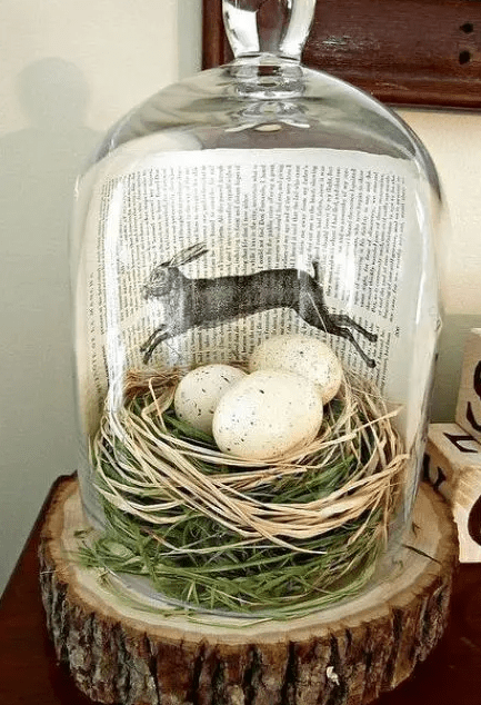 A modern terrarium with grass, hay, speckled eggs and a book page makes a beautiful rustic vintage Easter decoration