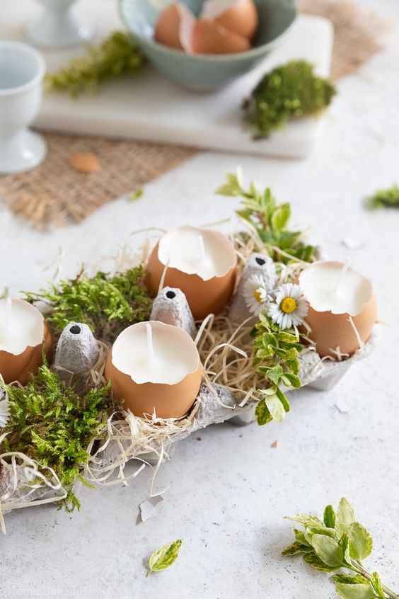 A rustic Easter centerpiece made from an egg carton with eggshell candles, moss and flowers is a cool idea