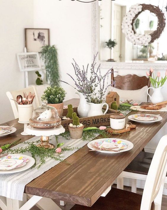 a rustic Easter table with a wooden tray with lavender and greenery, moss bunnies, greenery and printed plates