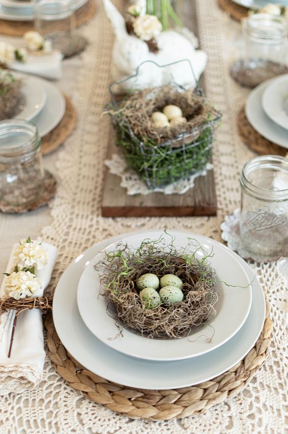 a rustic vintage Easter tablescape with doily runners, nests of eggs as decorations, neutral napkins and glasses instead of glasses