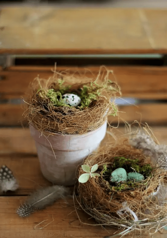 A whitewashed pot containing a bird's nest with moss and speckled eggs is a cool decoration for an Easter console or mantel