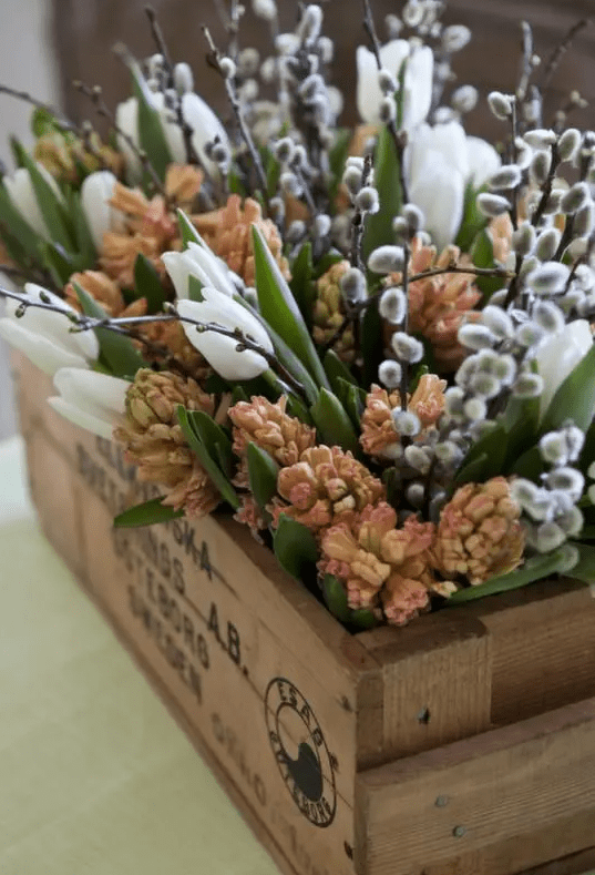 A wooden box filled with fresh spring blossoms, willow and leaves is a beautiful rustic decoration for Easter and spring