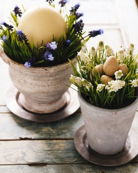 Beautiful rustic Easter decorations with whitewashed pots, greenery and flowers, and eggs of various sizes are a cool idea for a mantel, console or porch